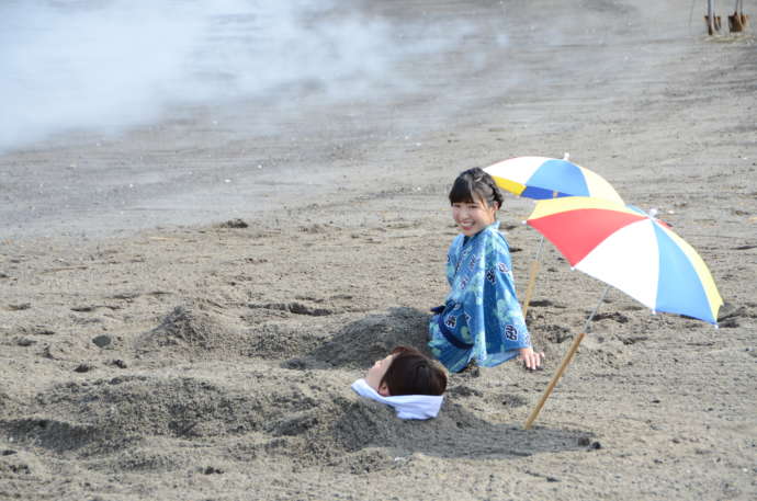指宿市の海辺で砂むし体験をする女性二人